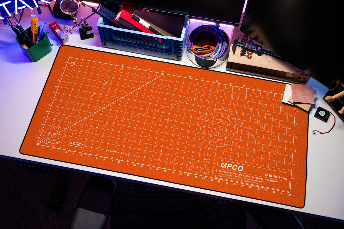 Draftpad desk mat in Orange / White, shown on a styled desk setup
