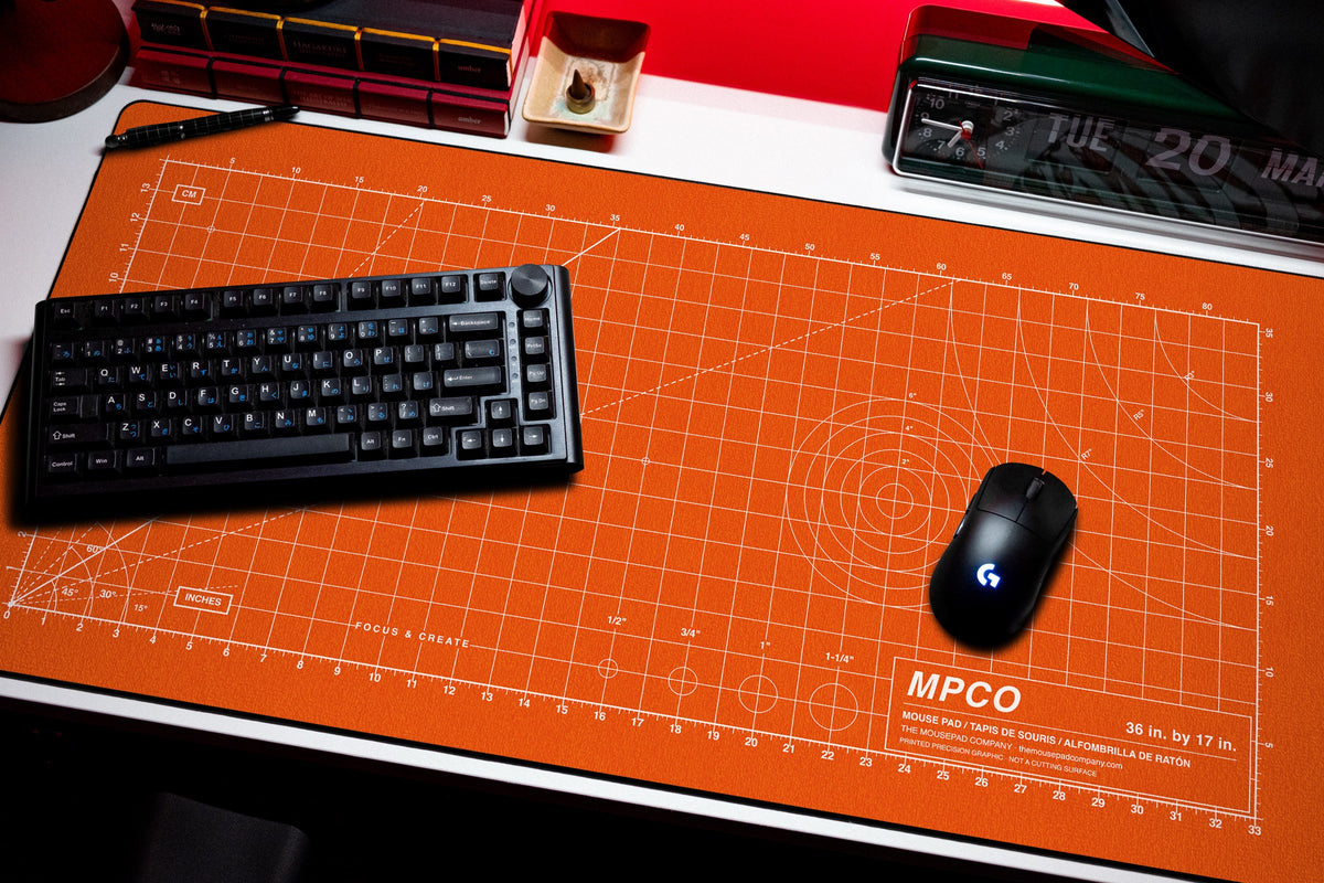 Draftpad desk mat in Orange / White, shown on a styled desk setup