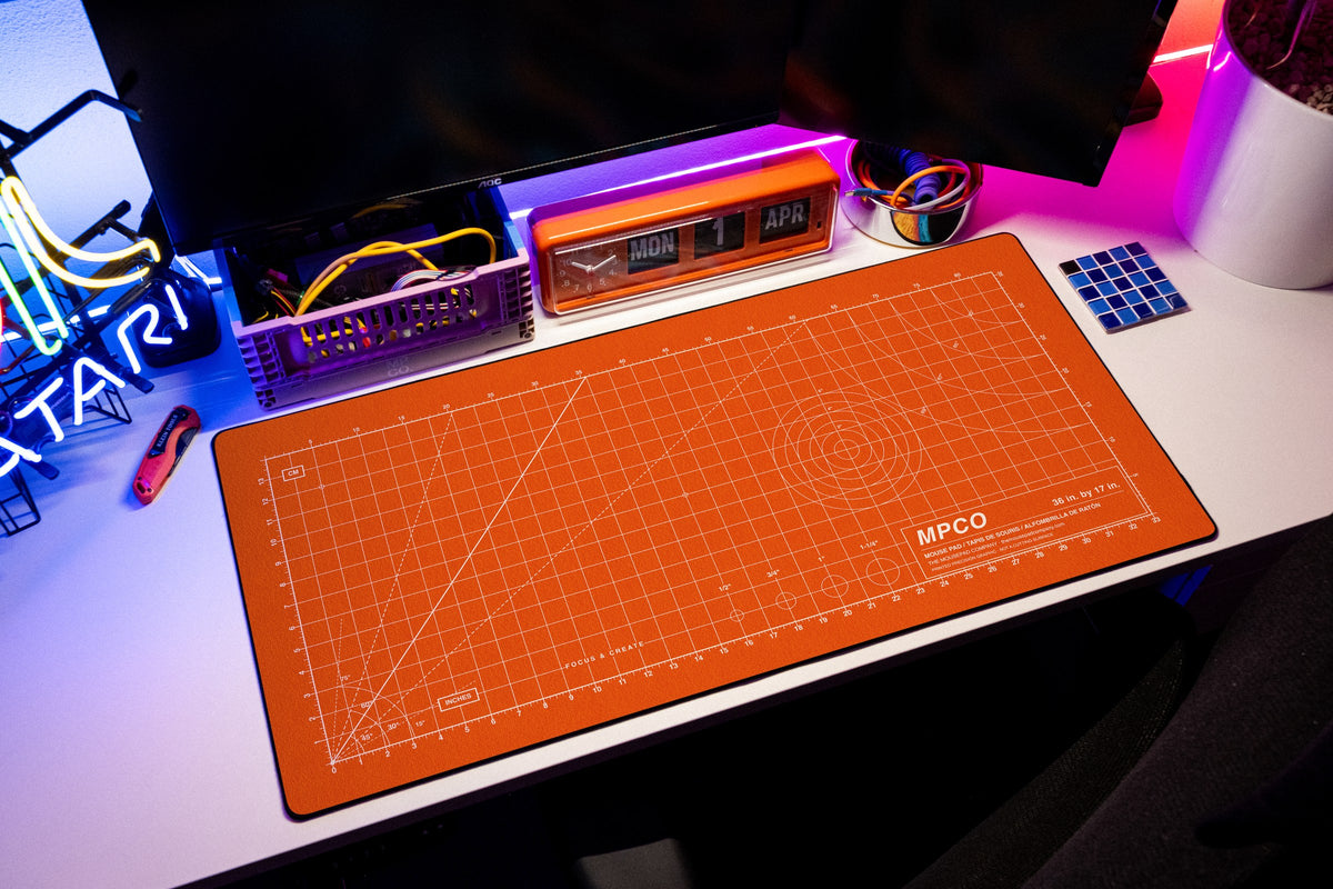 Draftpad desk mat in Orange / White, shown on a styled desk setup