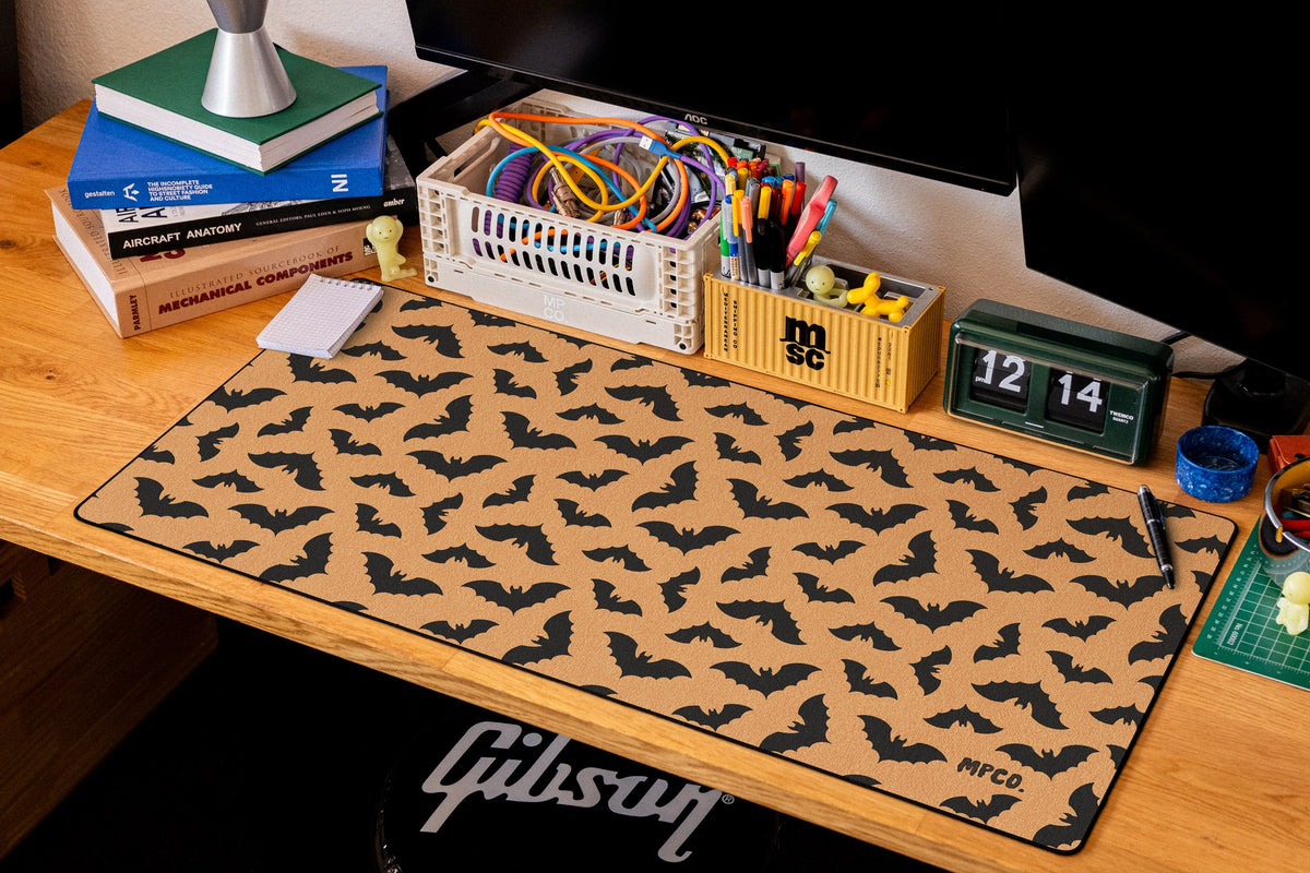 Bats desk mat in Orange, shown on a styled desk setup