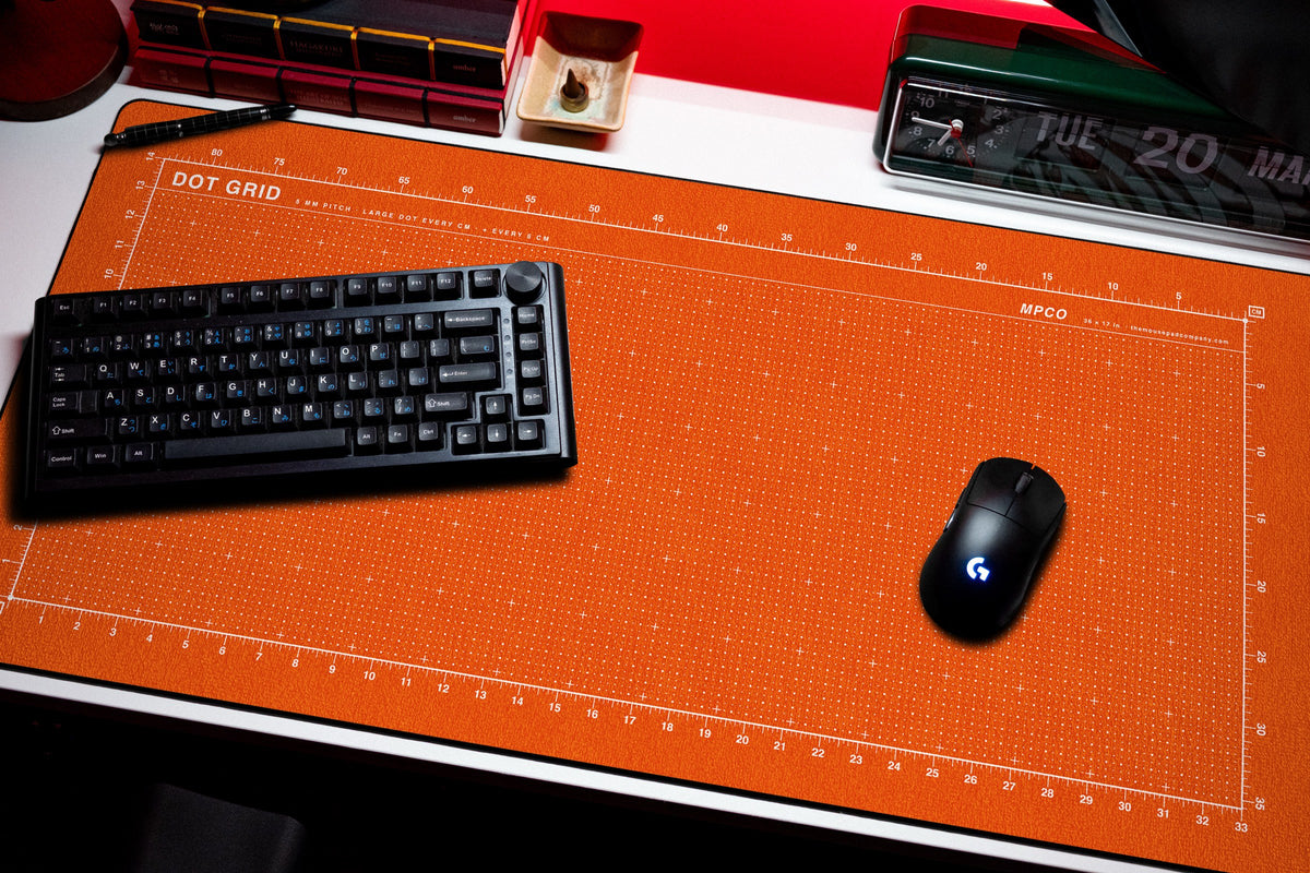 Dot Grid Pad desk mat in Orange / White, shown on a styled desk setup