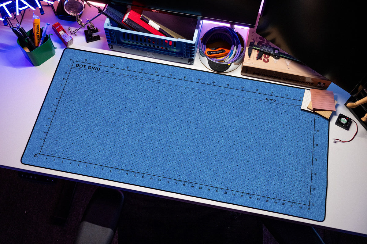 Dot Grid Pad desk mat in Swiss Blue, shown on a styled desk setup