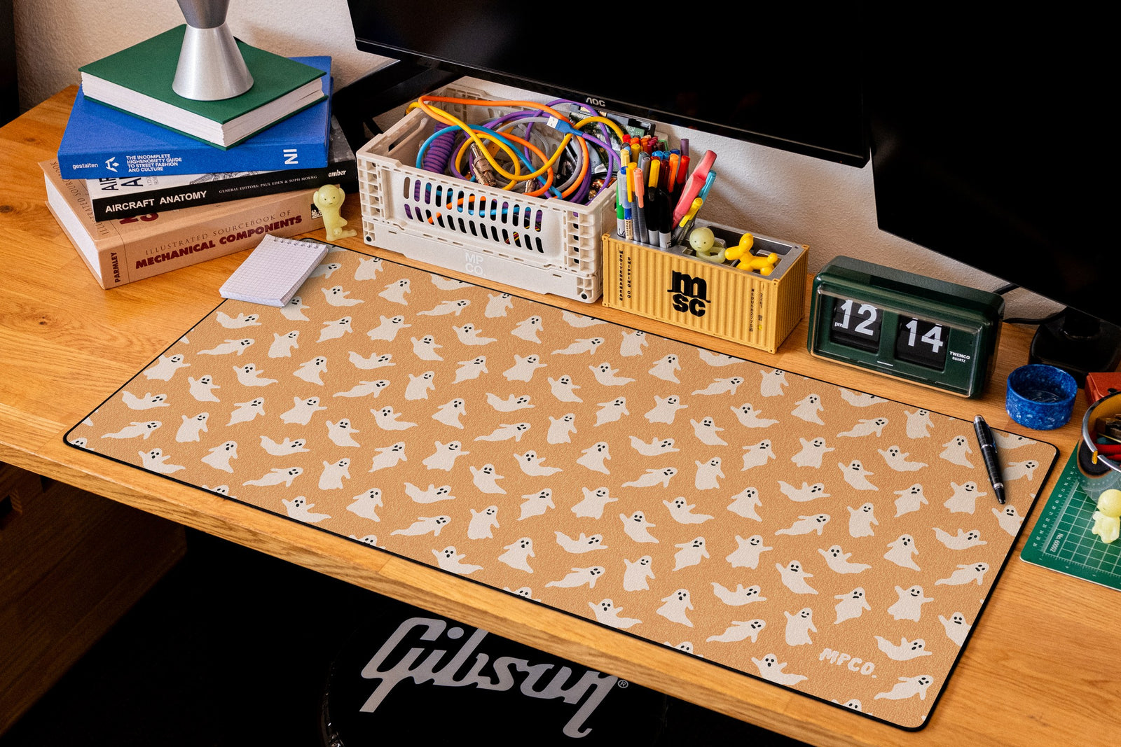 Ghosts desk mat in Orange, shown on a styled desk setup