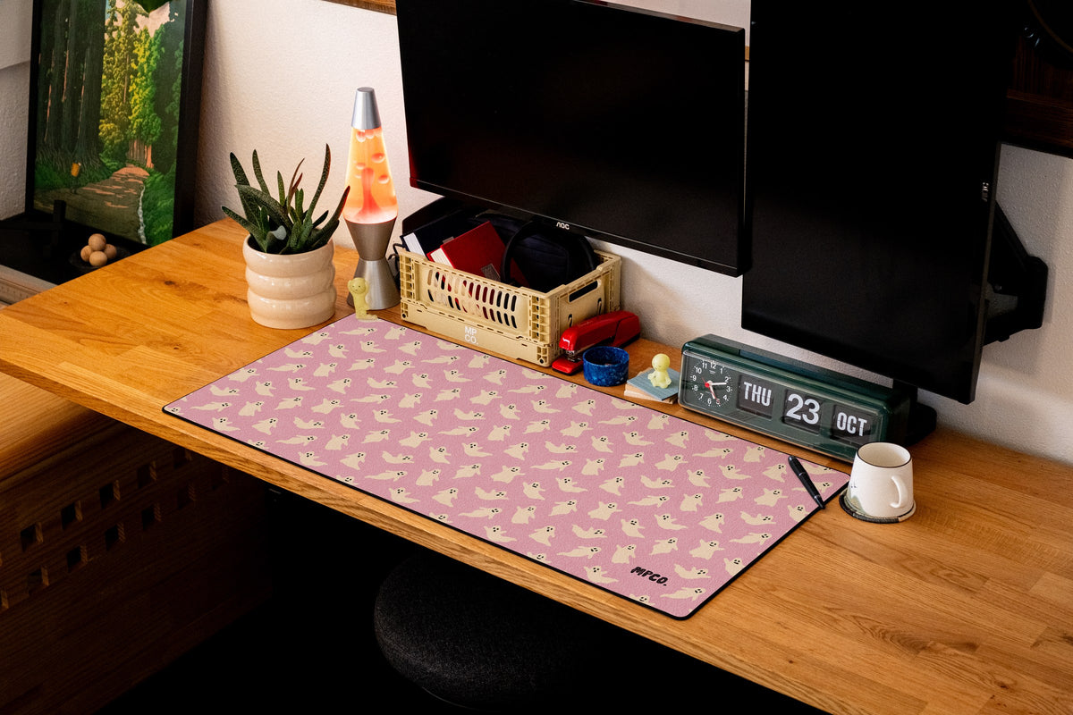 Ghosts desk mat in Pink, shown on a styled desk setup