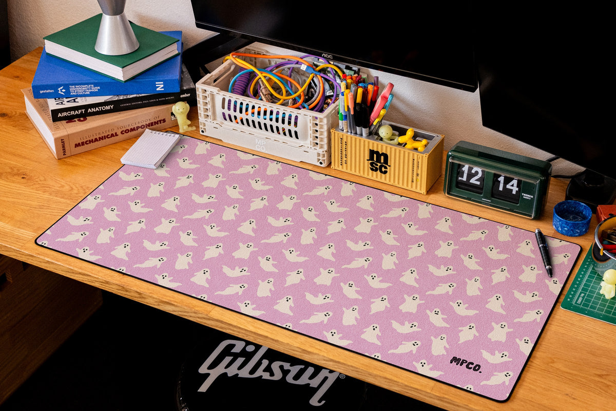 Ghosts desk mat in Pink, shown on a styled desk setup