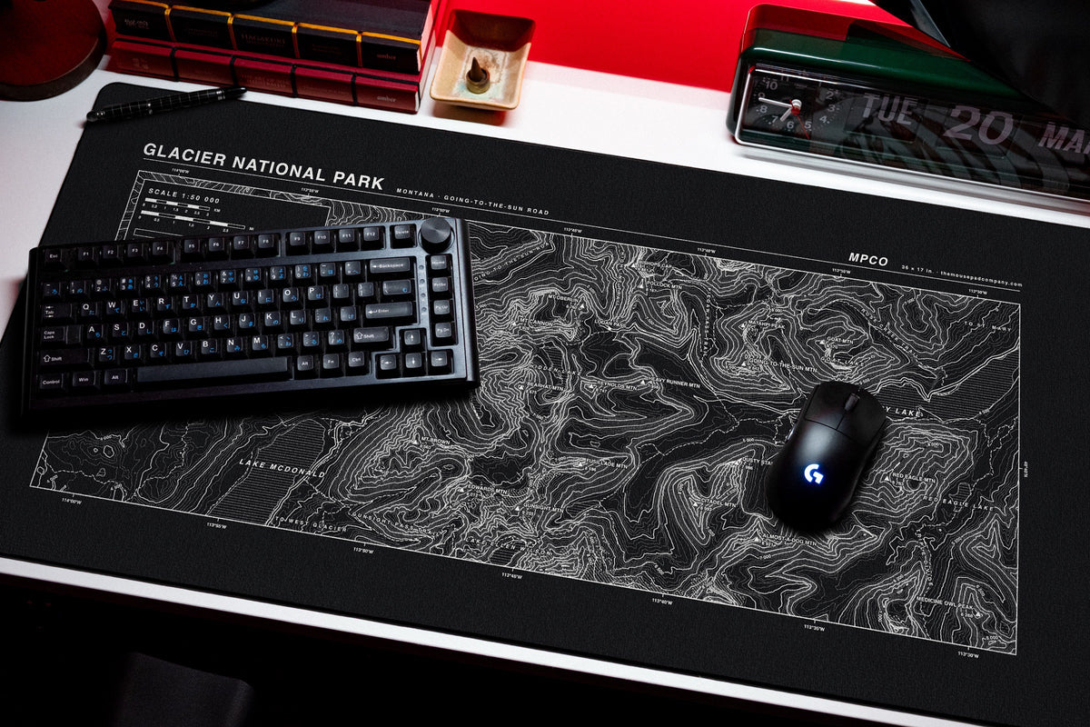 Glacier National Park Topo Pad desk mat in Black / White, shown on a styled desk setup