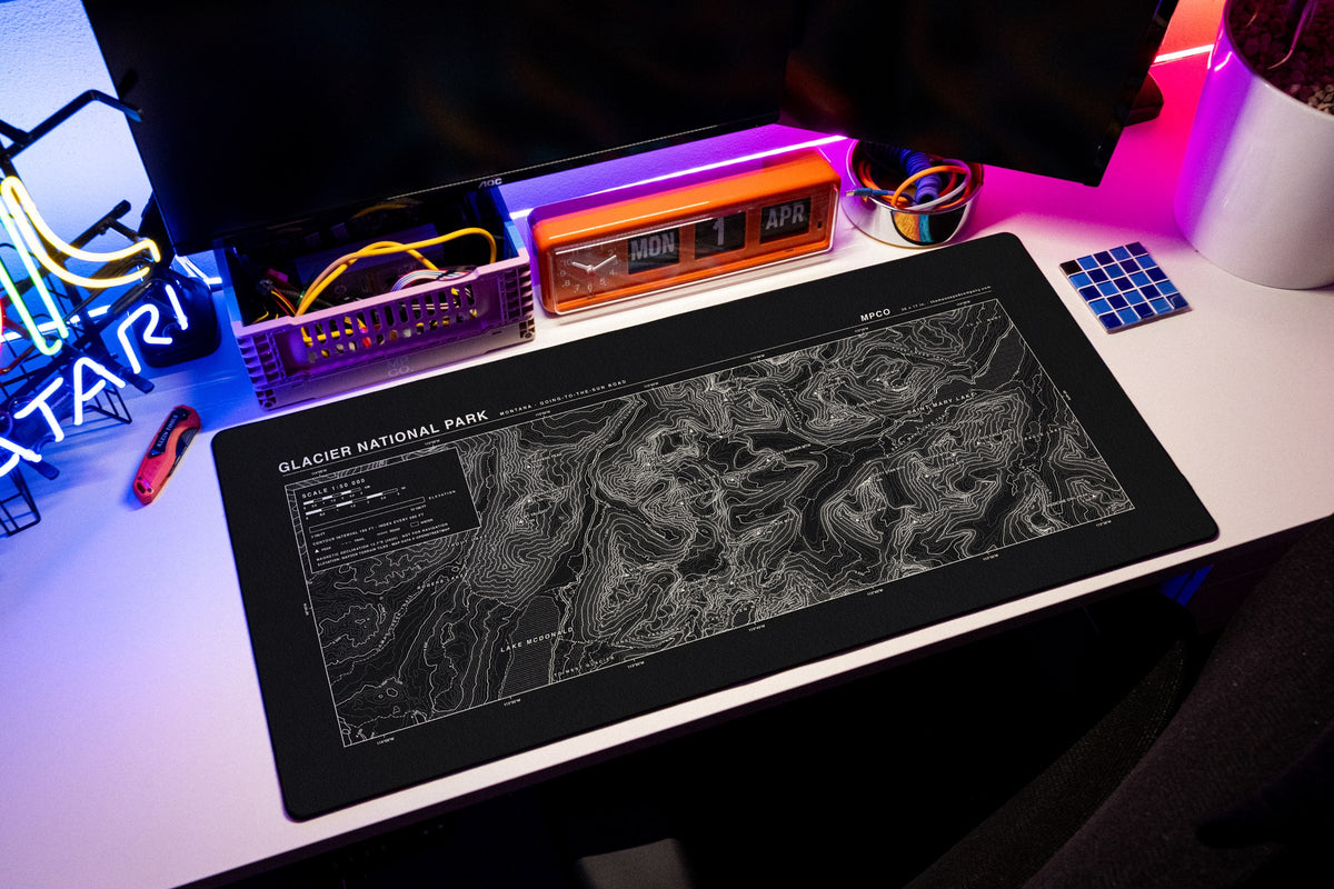 Glacier National Park Topo Pad desk mat in Black / White, shown on a styled desk setup