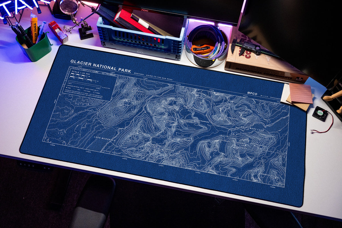 Glacier National Park Topo Pad desk mat in Blue / White, shown on a styled desk setup