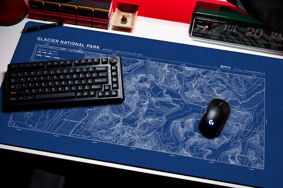 Glacier National Park Topo Pad desk mat in Blue / White, shown on a styled desk setup