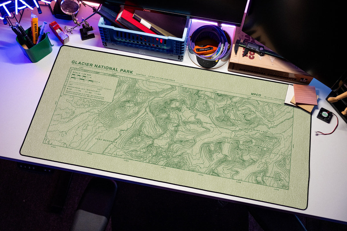 Glacier National Park Topo Pad desk mat in Buff / Green, shown on a styled desk setup
