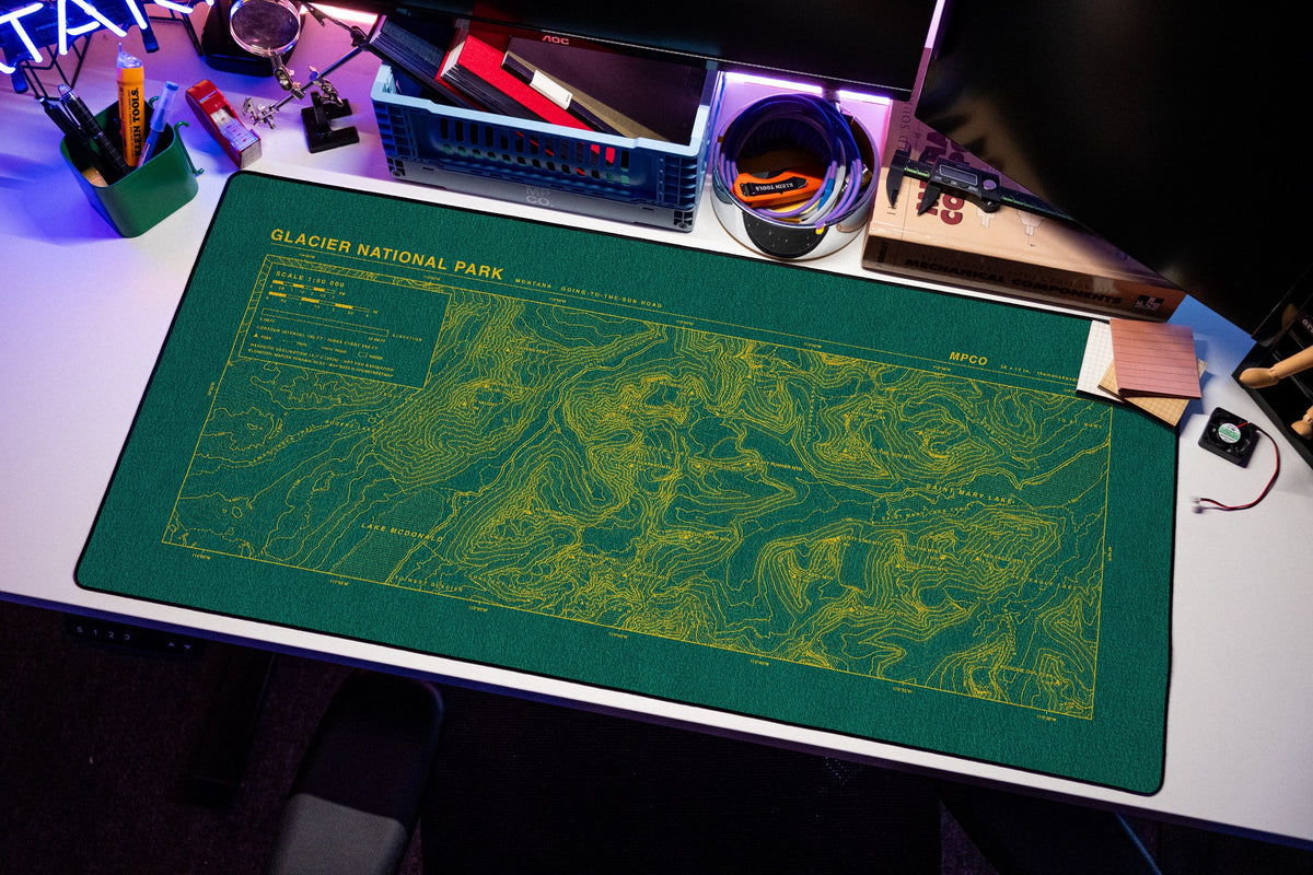 Glacier National Park Topo Pad desk mat in Green / Yellow, shown on a styled desk setup