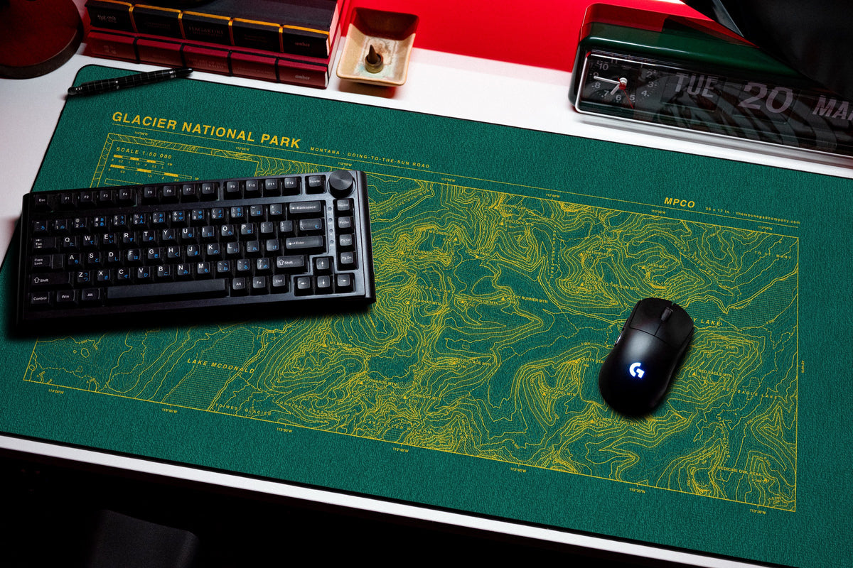 Glacier National Park Topo Pad desk mat in Green / Yellow, shown on a styled desk setup