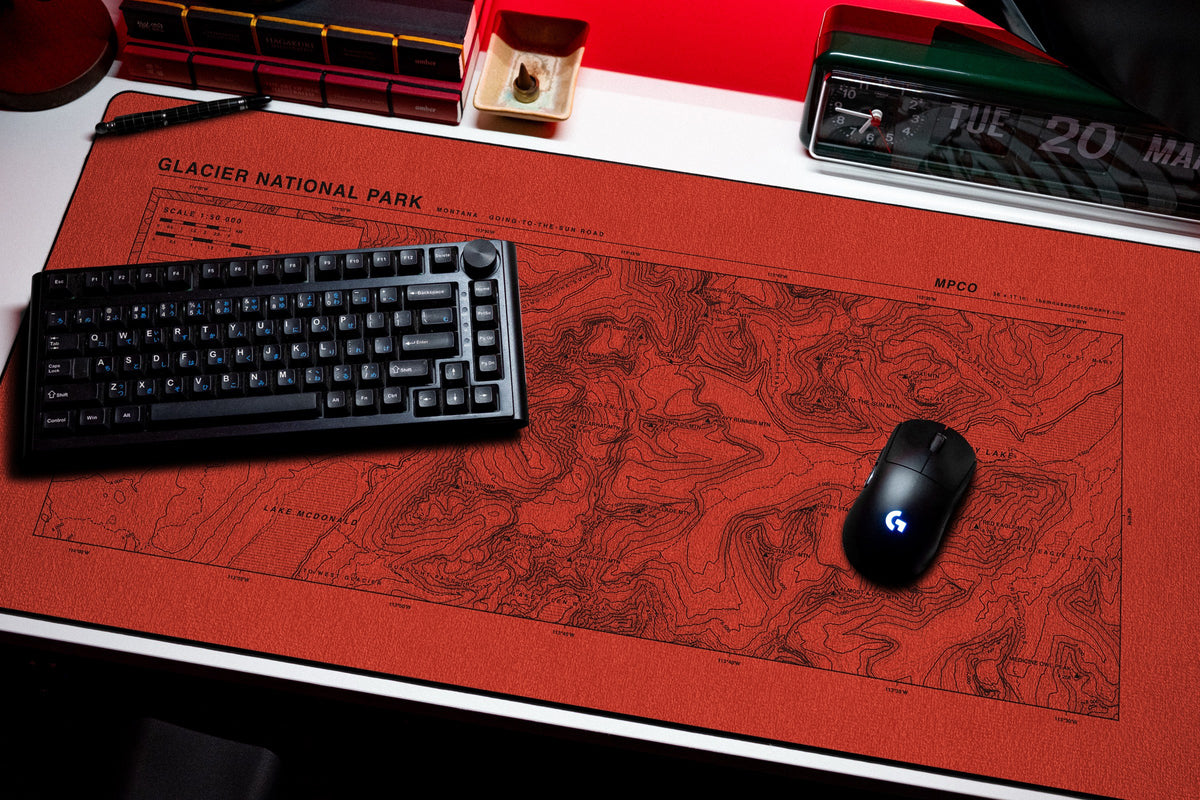 Glacier National Park Topo Pad desk mat in Red / Black, shown on a styled desk setup