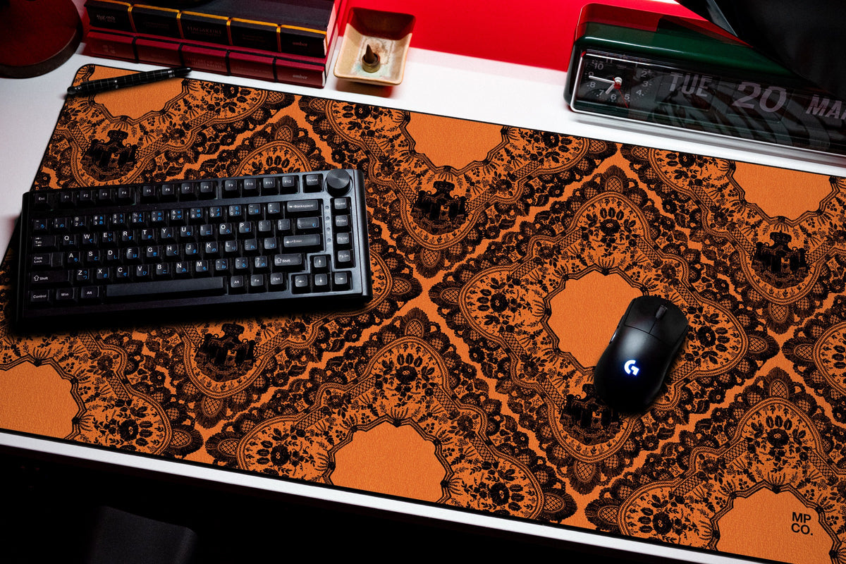 Gothic Diamonds desk mat in Black Lace on Orange, shown on a styled desk setup