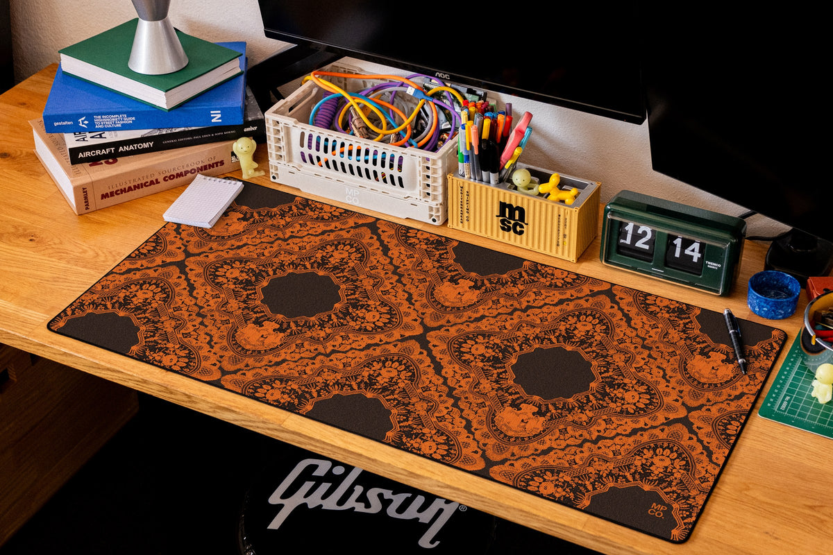 Gothic Diamonds desk mat in Orange Lace on Black, shown on a styled desk setup