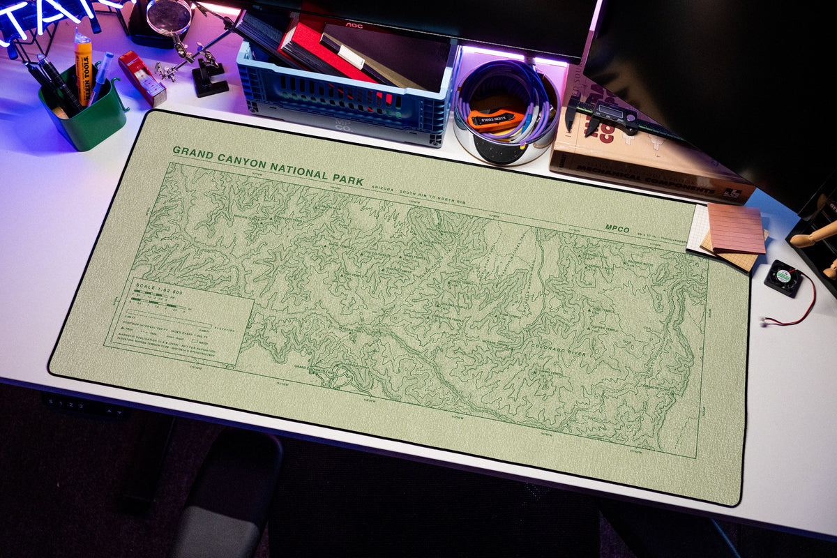 Grand Canyon National Park Topo Pad desk mat in Buff / Green, shown on a styled desk setup