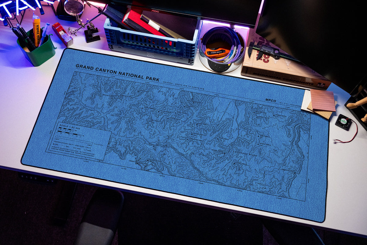 Grand Canyon National Park Topo Pad desk mat in Swiss Blue, shown on a styled desk setup