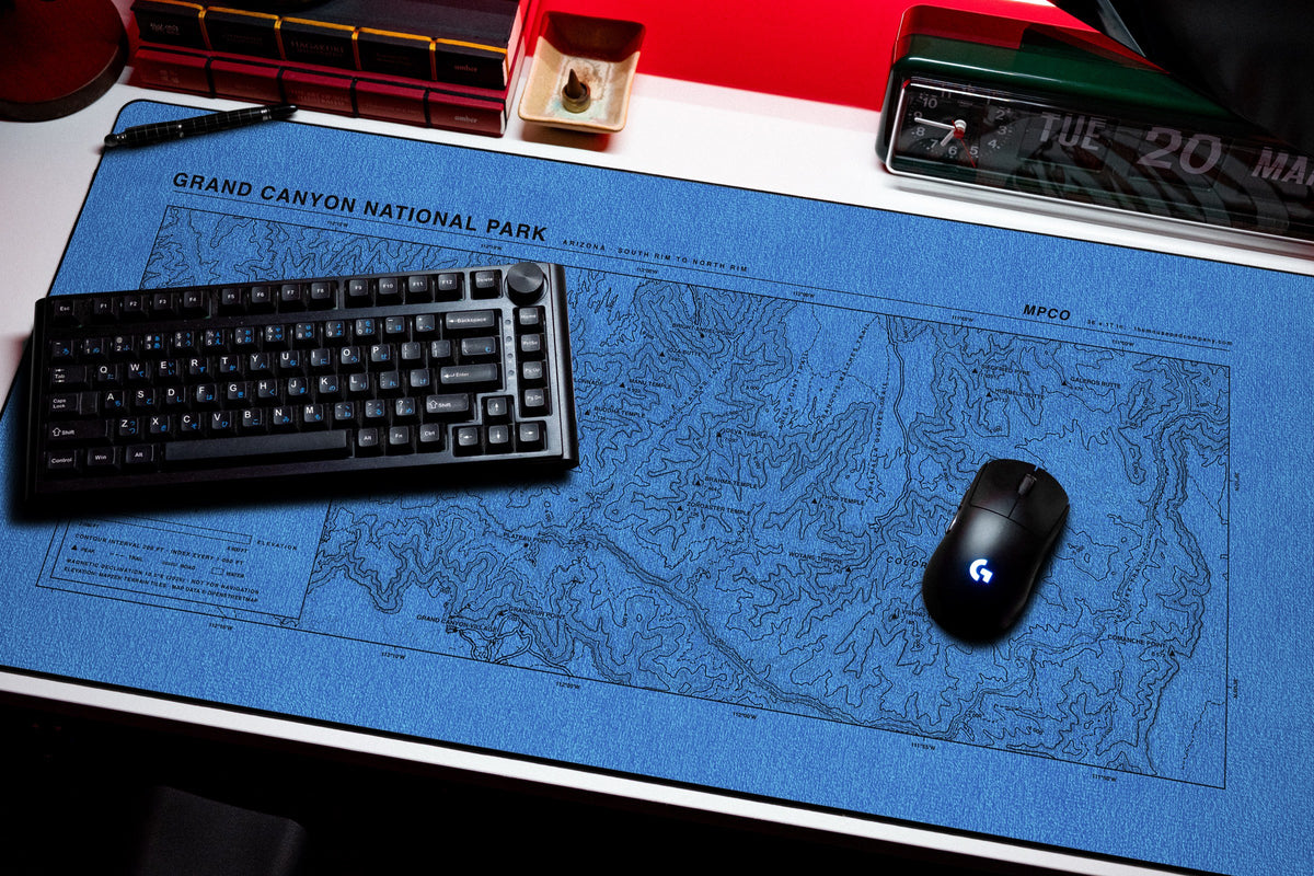 Grand Canyon National Park Topo Pad desk mat in Swiss Blue, shown on a styled desk setup