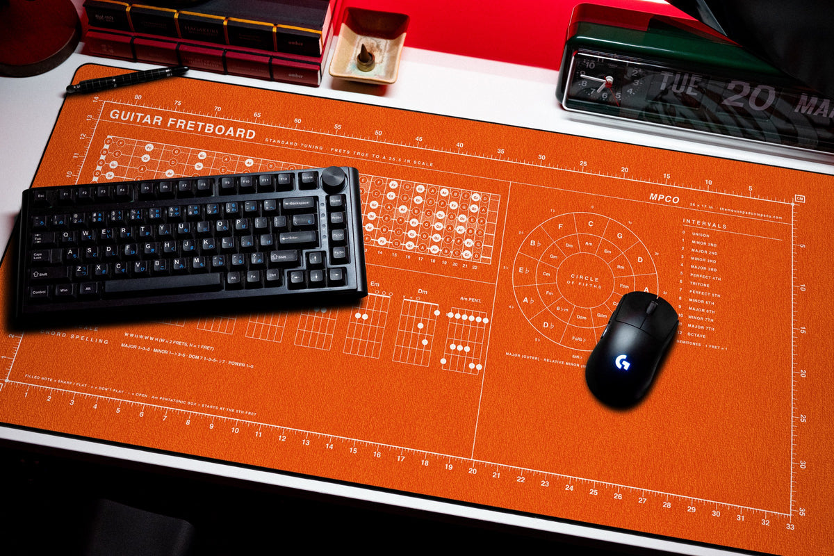 Guitar Fretboard Pad desk mat in Orange / White, shown on a styled desk setup