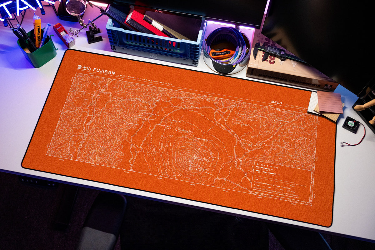 Mount Fuji Topo Pad desk mat in Orange / White, shown on a styled desk setup