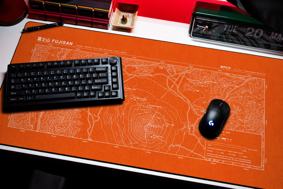 Mount Fuji Topo Pad desk mat in Orange / White, shown on a styled desk setup