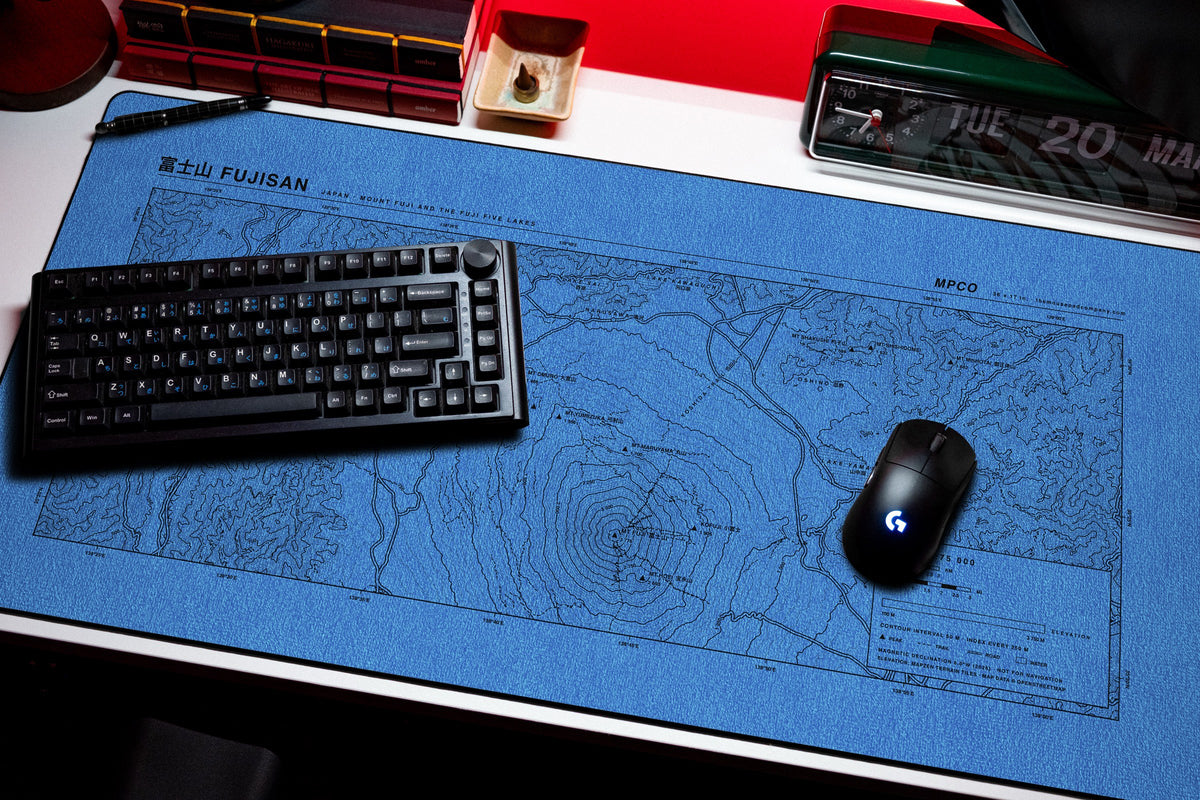 Mount Fuji Topo Pad desk mat in Swiss Blue, shown on a styled desk setup