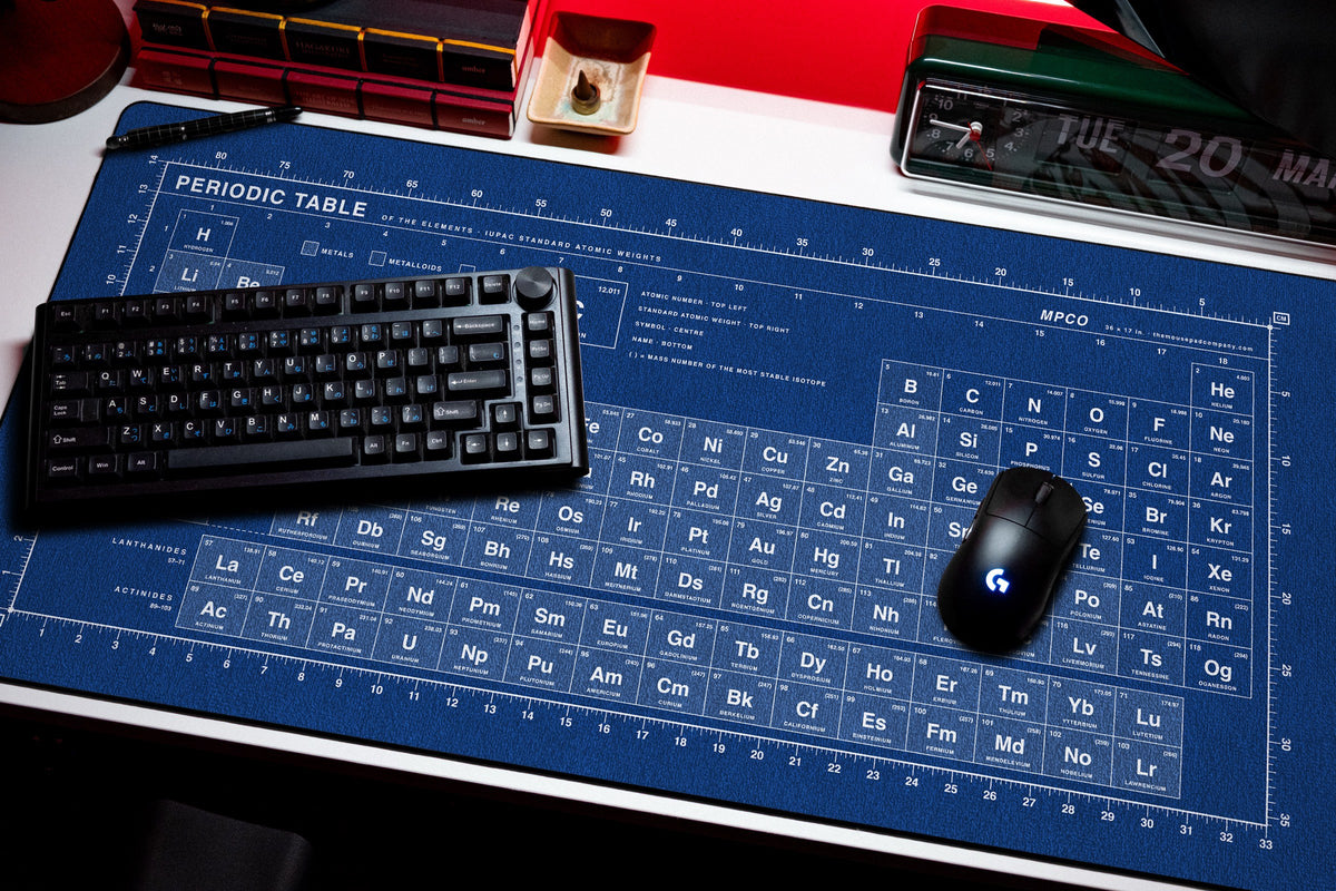 Periodic Table Pad desk mat in Blue / White, shown on a styled desk setup