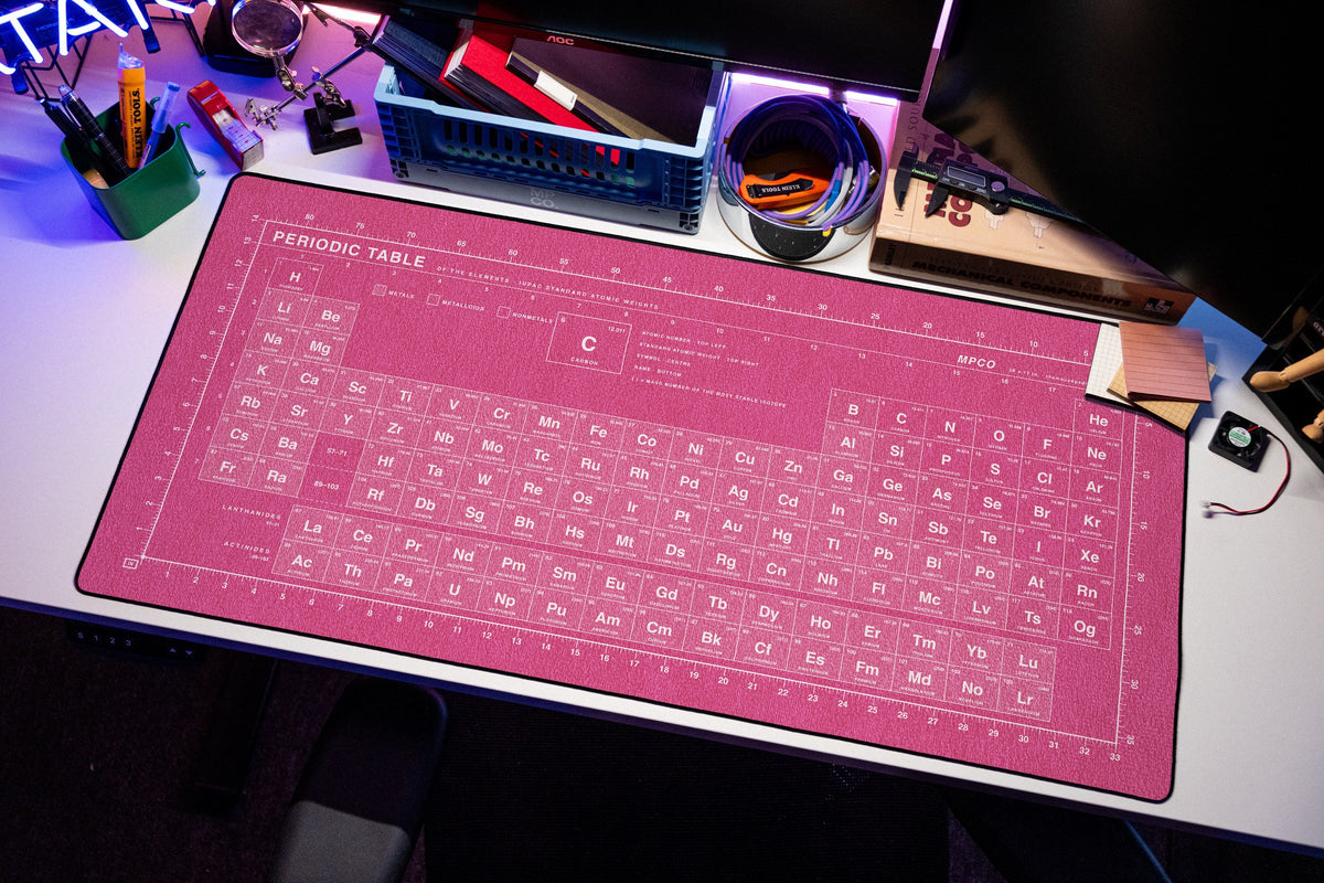 Periodic Table Pad desk mat in Pink / White, shown on a styled desk setup
