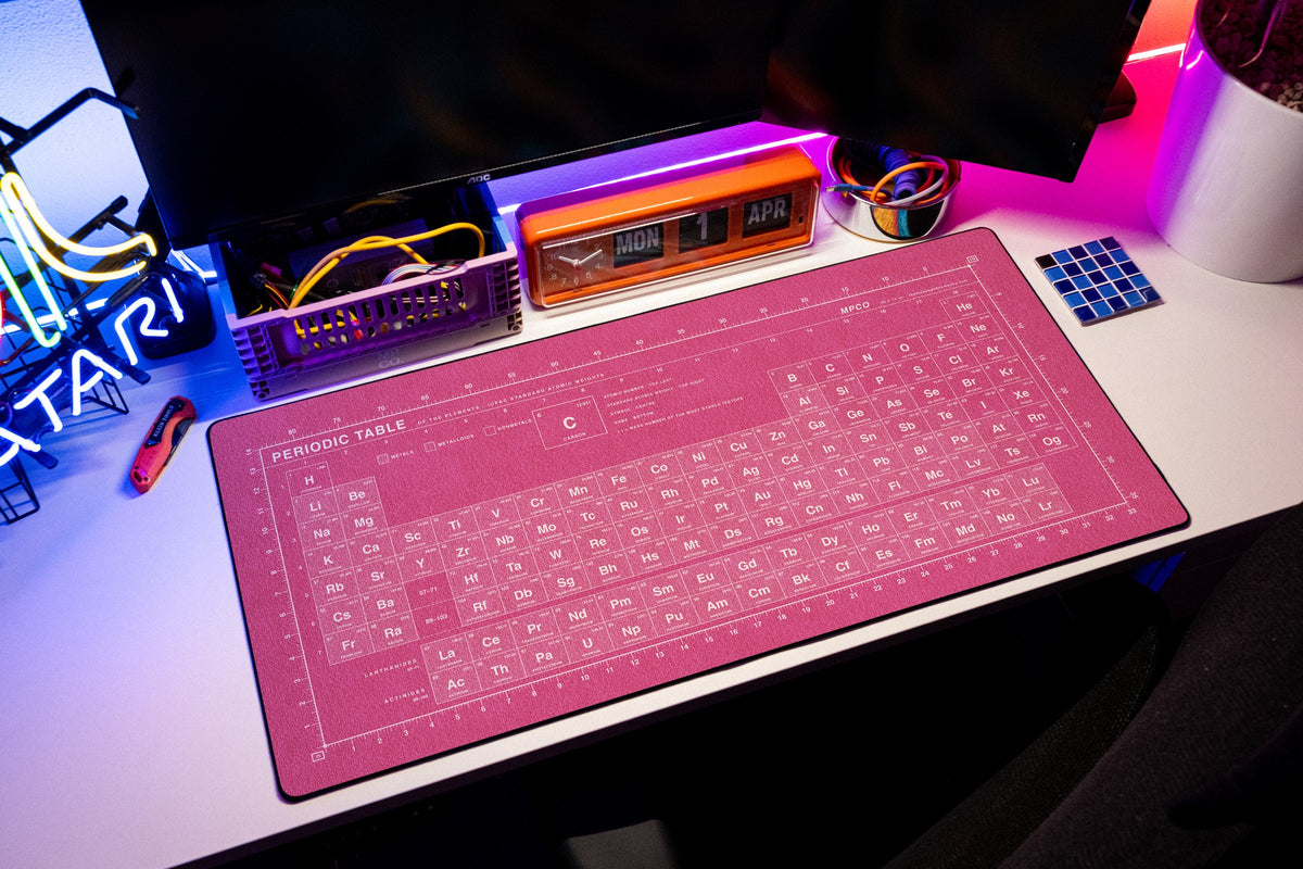 Periodic Table Pad desk mat in Pink / White, shown on a styled desk setup
