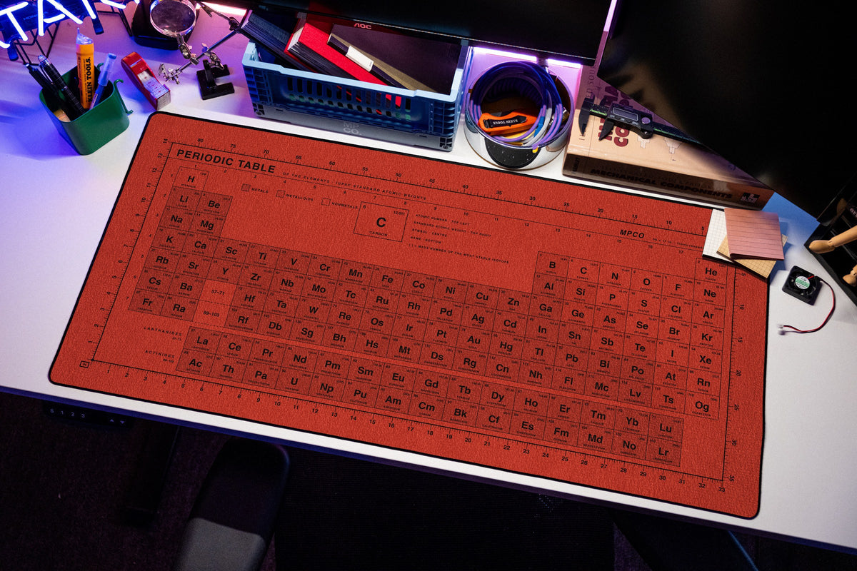 Periodic Table Pad desk mat in Red / Black, shown on a styled desk setup