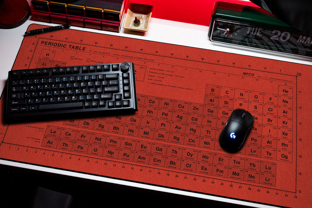 Periodic Table Pad desk mat in Red / Black, shown on a styled desk setup