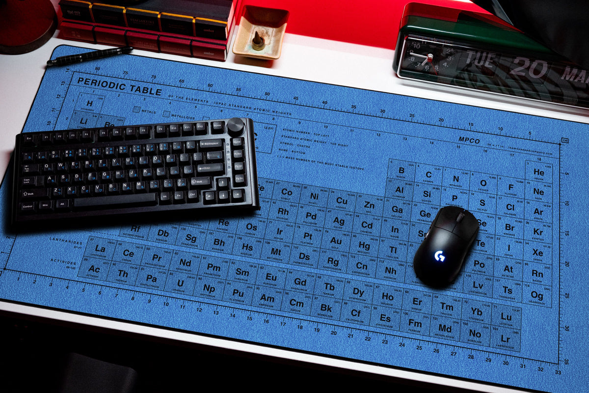 Periodic Table Pad desk mat in Swiss Blue, shown on a styled desk setup