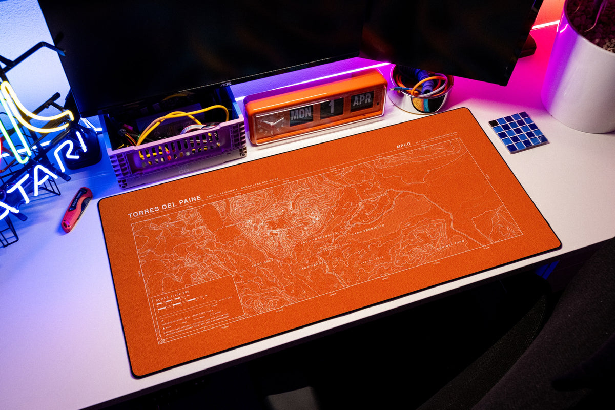Torres del Paine Topo Pad desk mat in Orange / White, shown on a styled desk setup