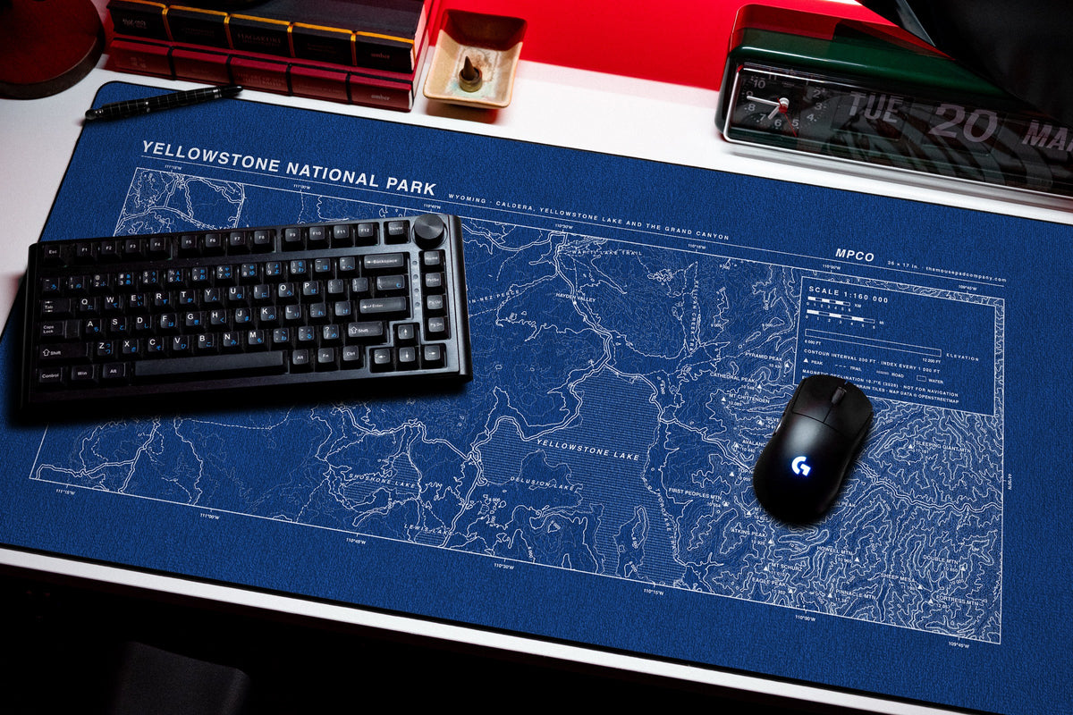Yellowstone National Park Topo Pad desk mat in Blue / White, shown on a styled desk setup