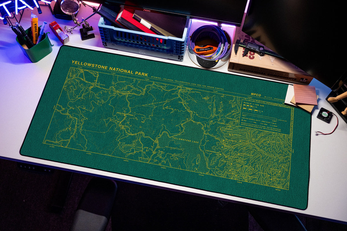 Yellowstone National Park Topo Pad desk mat in Green / Yellow, shown on a styled desk setup