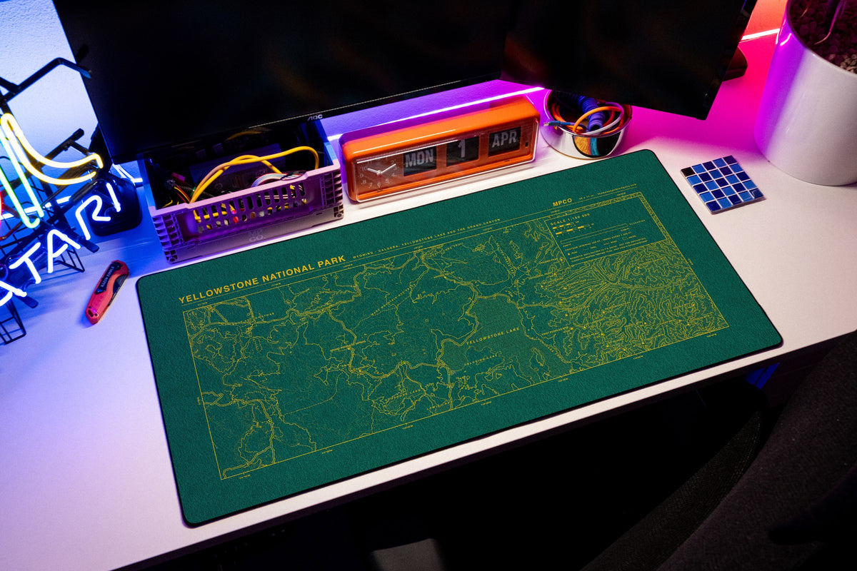 Yellowstone National Park Topo Pad desk mat in Green / Yellow, shown on a styled desk setup