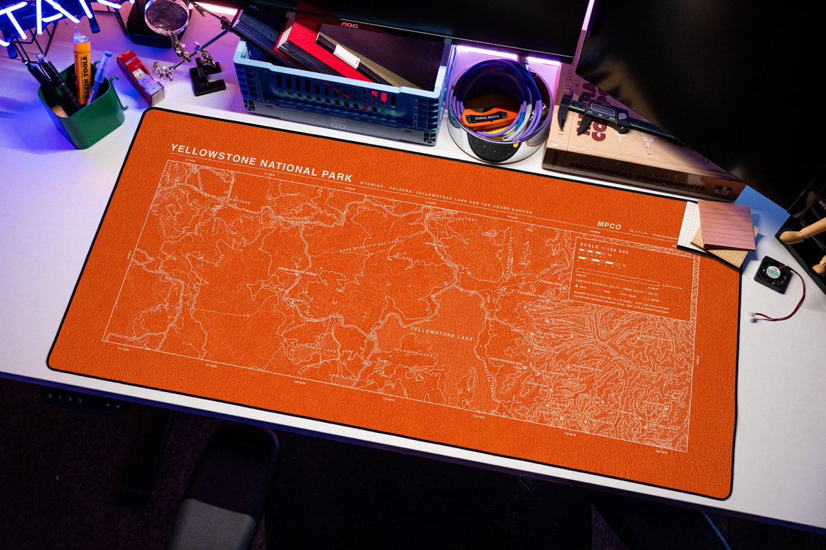 Yellowstone National Park Topo Pad desk mat in Orange / White, shown on a styled desk setup