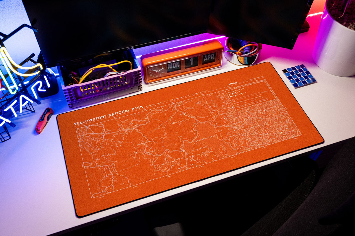 Yellowstone National Park Topo Pad desk mat in Orange / White, shown on a styled desk setup