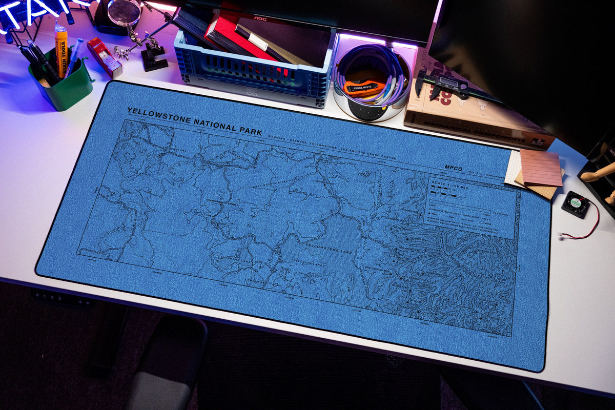 Yellowstone National Park Topo Pad desk mat in Swiss Blue, shown on a styled desk setup