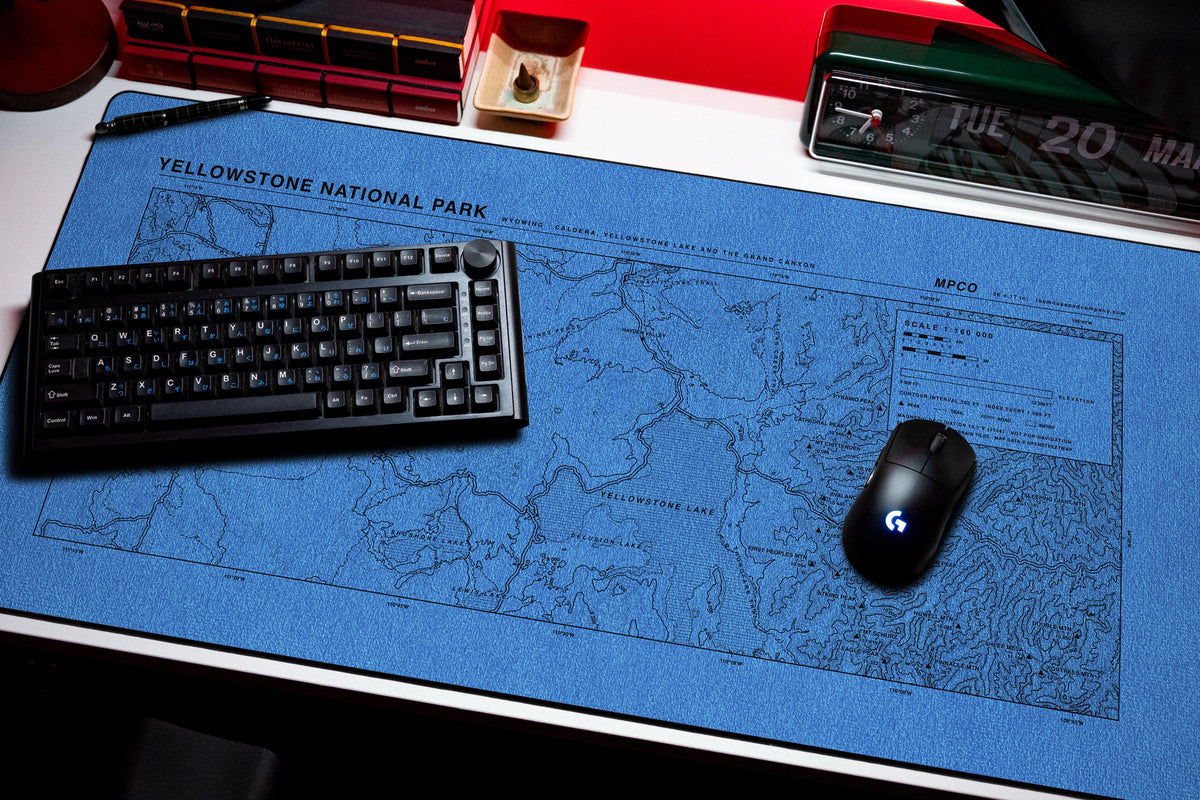 Yellowstone National Park Topo Pad desk mat in Swiss Blue, shown on a styled desk setup