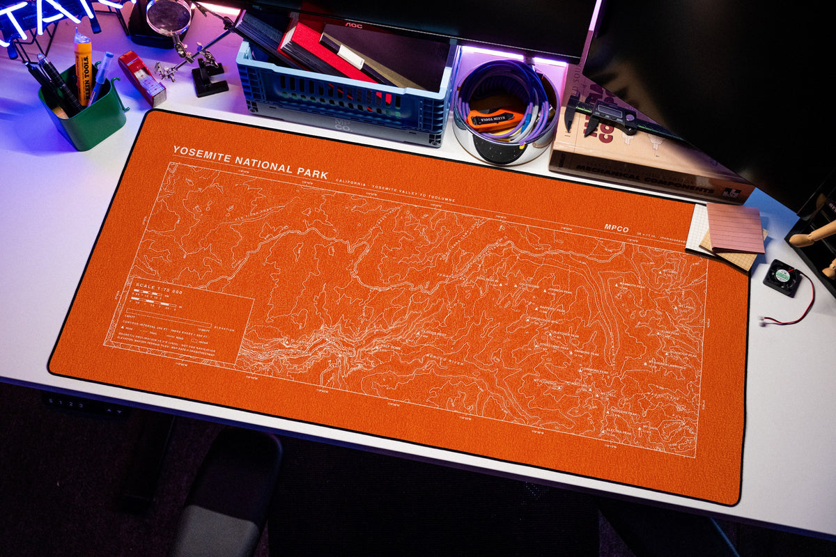 Yosemite National Park Topo Pad desk mat in Orange / White, shown on a styled desk setup