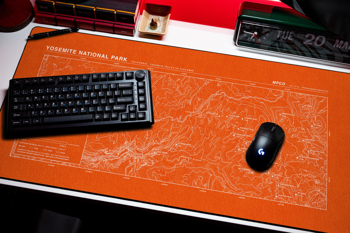 Yosemite National Park Topo Pad desk mat in Orange / White, shown on a styled desk setup