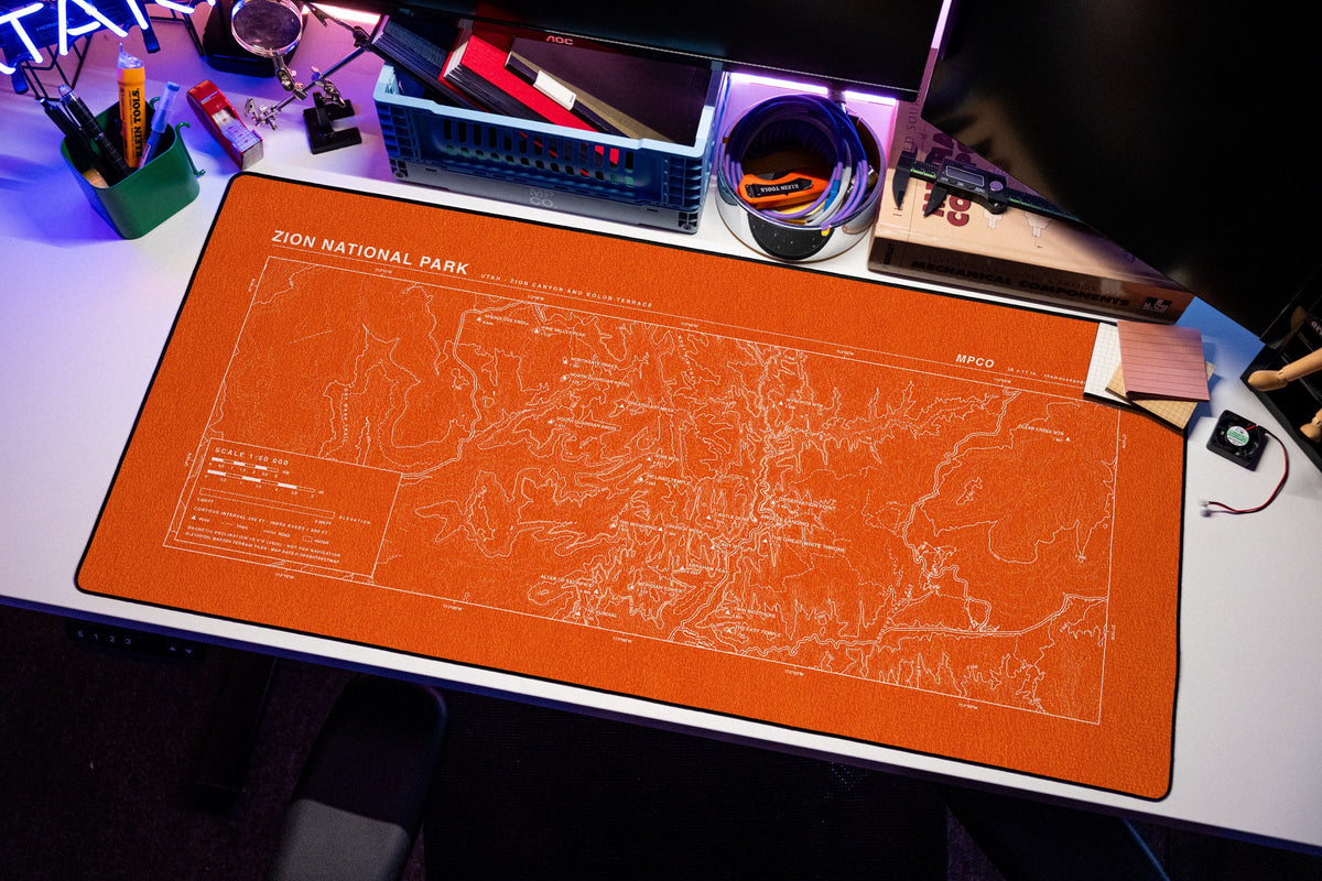 Zion National Park Topo Pad desk mat in Orange / White, shown on a styled desk setup