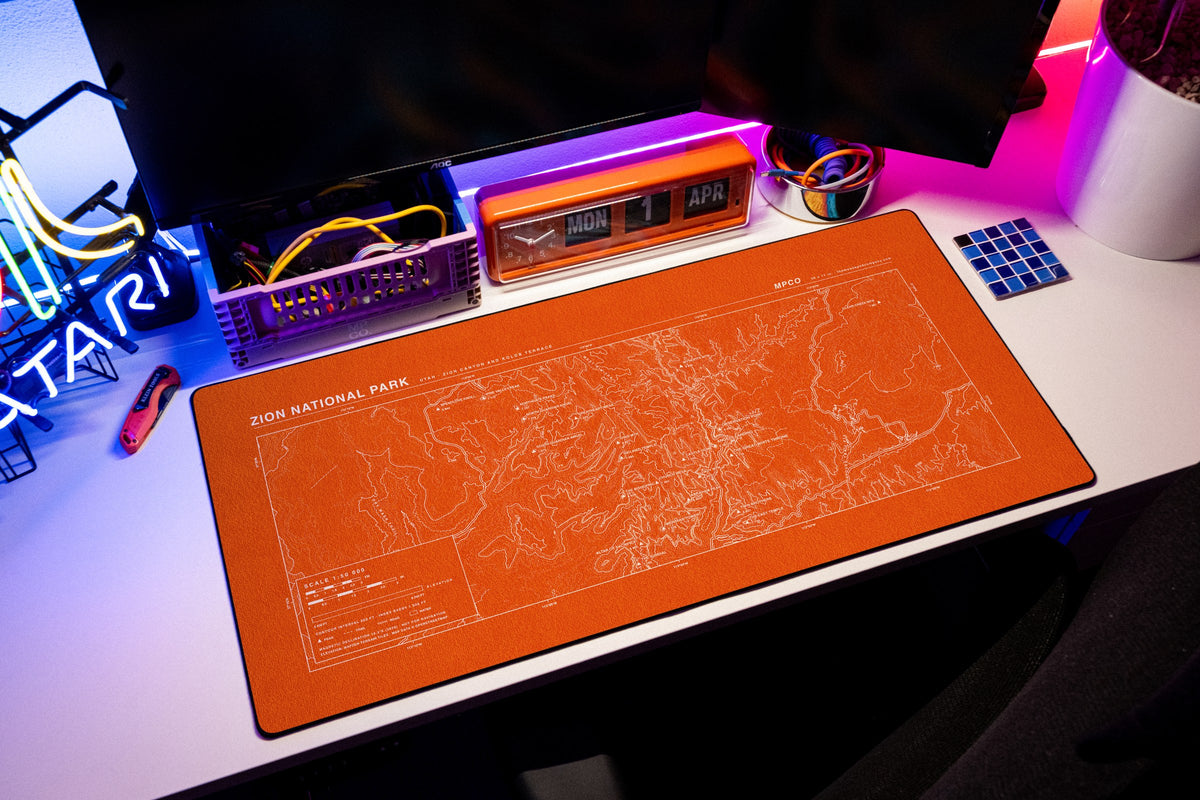 Zion National Park Topo Pad desk mat in Orange / White, shown on a styled desk setup