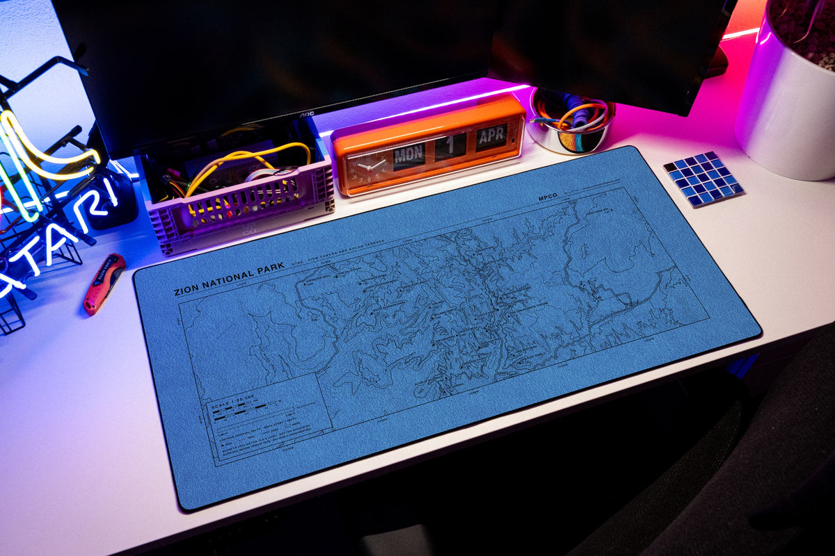 Zion National Park Topo Pad desk mat in Swiss Blue, shown on a styled desk setup